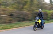 Motard roulant debout sur la Suzuki V-Strom 800 DE en coloris jaune.