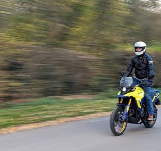 Motard roulant debout sur la Suzuki V-Strom 800 DE en coloris jaune.