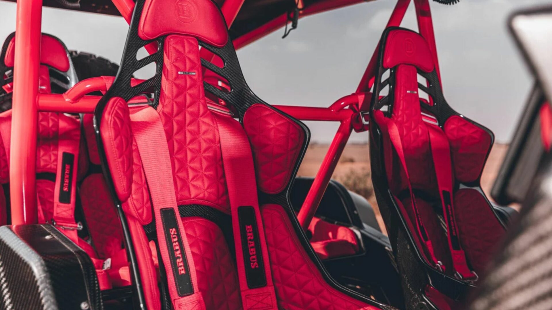 Sièges baquets en carbone et tissu rouge TechFX du Brabus Crawler avec harnais de sécurité et arceau de cage rouge.