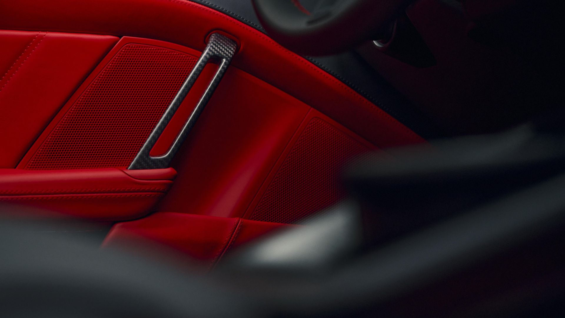 Poignée de porte légère en fibre de carbone (PRFC) sur panneau de porte en cuir Rouge indien d'une Porsche 911 GT3 cabriolet.