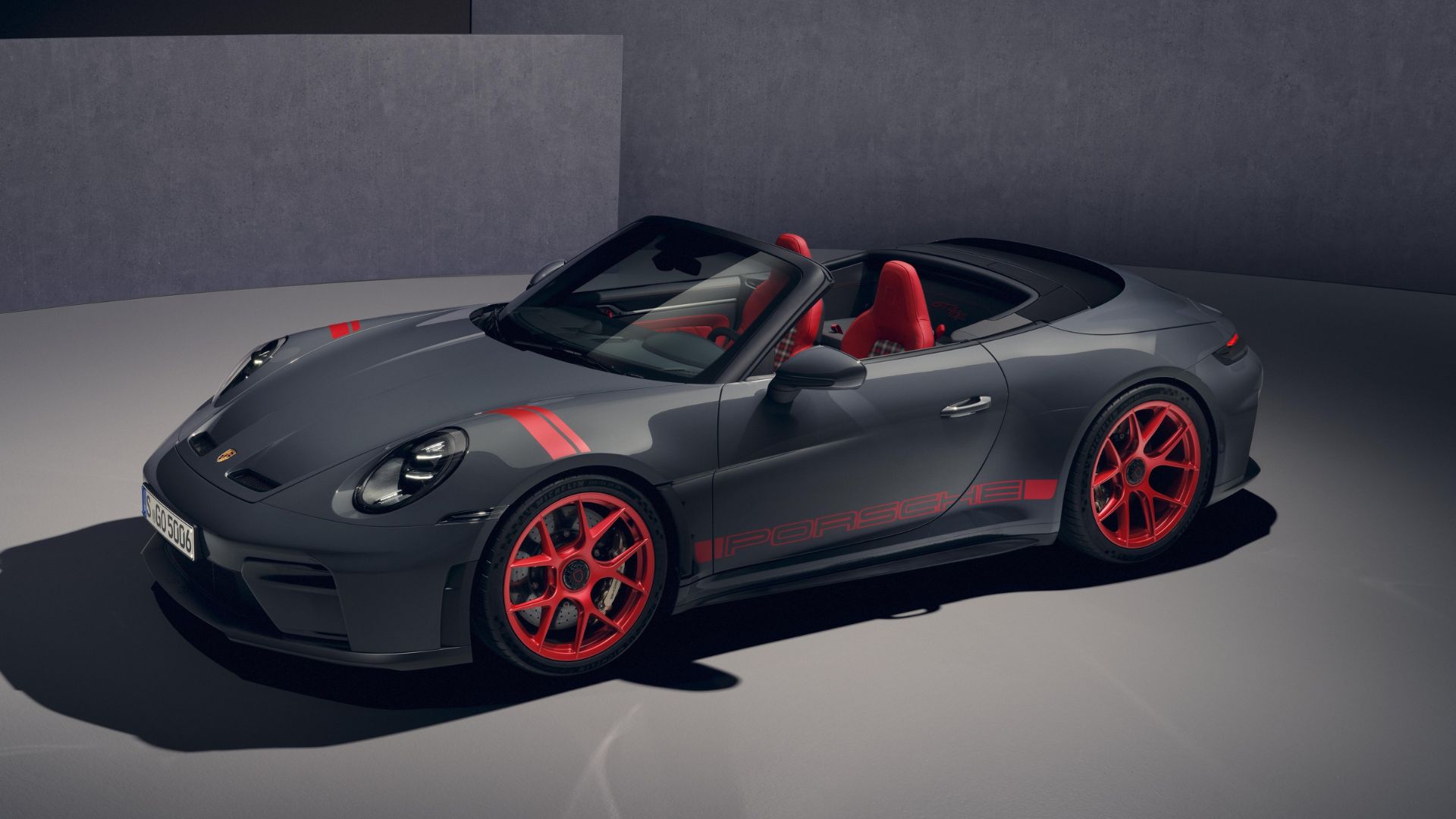 Porsche 911 GT3 cabriolet (S/C) grise avec jantes rouges magnésium et intérieur bicolore rouge/gris, vue de l'avant en studio.