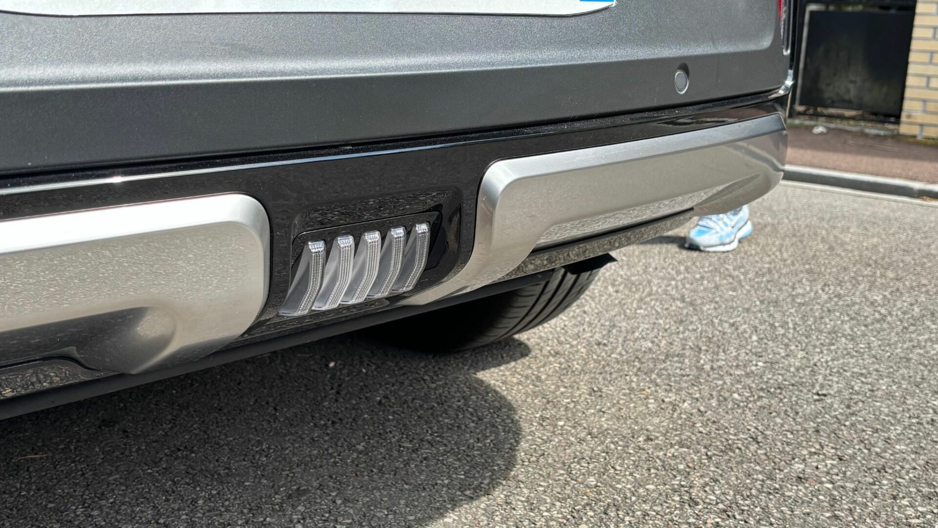 Gros plan sur le feu de recul central à stries translucides et le sabot de protection façon alu du bouclier arrière du Kia Niro Hybride 2026