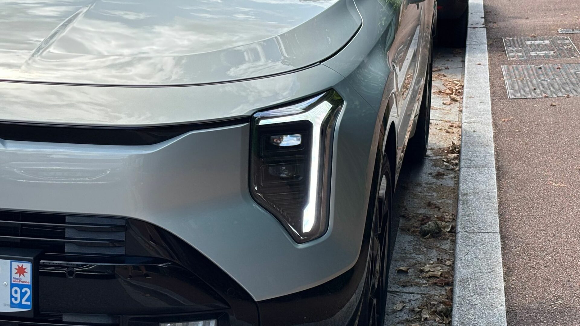 Gros plan sur l'optique de phare LED verticale et la signature lumineuse diurne du Kia Niro Hybride 2026 Gris Ivoire