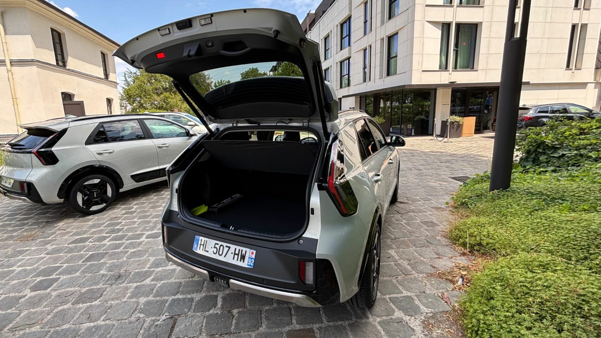 Vue arrière du Kia Niro Hybride 2026 Gris Ivoire avec hayon ouvert dévoilant le volume du coffre de 430 litres