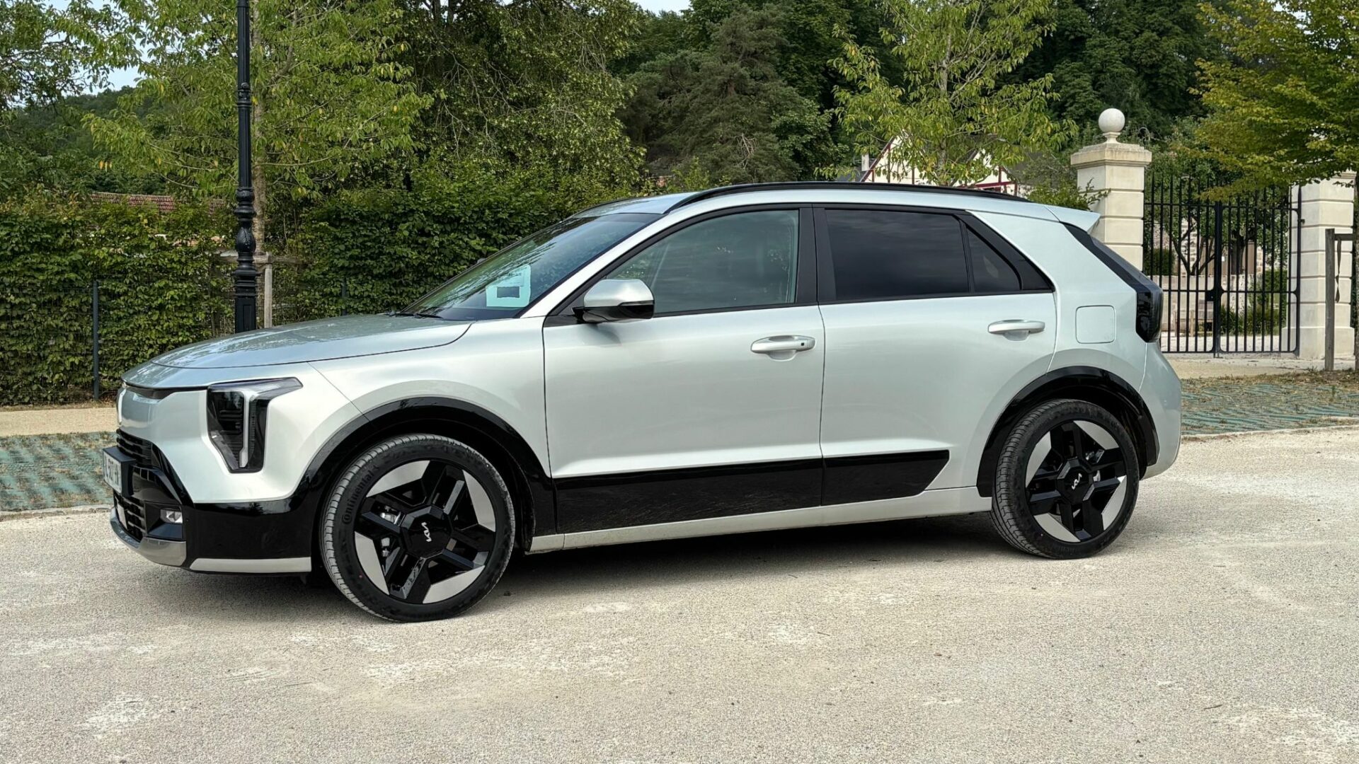 Kia Niro Hybride 2026 Gris Ivoire vu de trois-quarts profil sur un parking extérieur