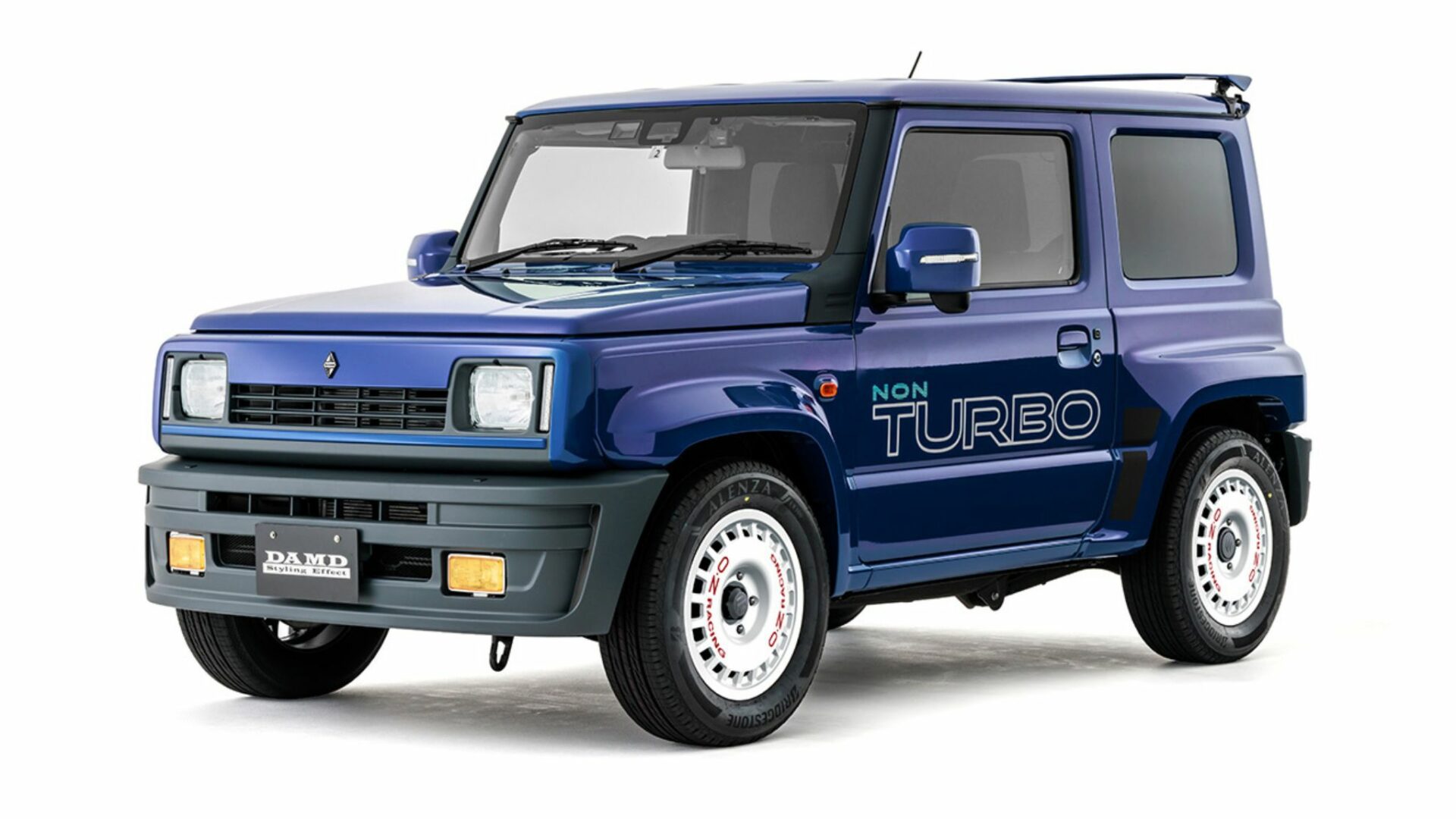 Vue trois-quarts avant studio du Suzuki Jimny R5 bleu DAMD avec stickers Non Turbo et jantes blanches OZ Racing