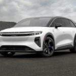 Vue de trois-quarts avant du Lucid Gravity GT-S blanc montrant son bouclier agressif, ses feux LED affinés et son badge d'ours bleu sur l'aile
