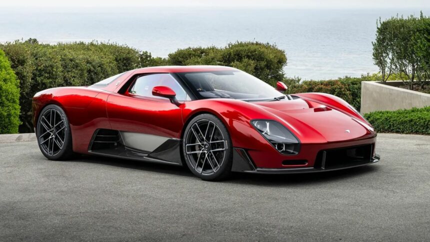 Vue de trois-quarts avant de la McLaren 6GT couleur rouge métallisé stationnée en bord de mer avec ses lignes néo-rétro