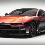 Vue de trois-quarts avant de l'Aston Martin Valen couleur rouge et bronze métallisé avec ses phares LED effilés et sa lame avant en carbone