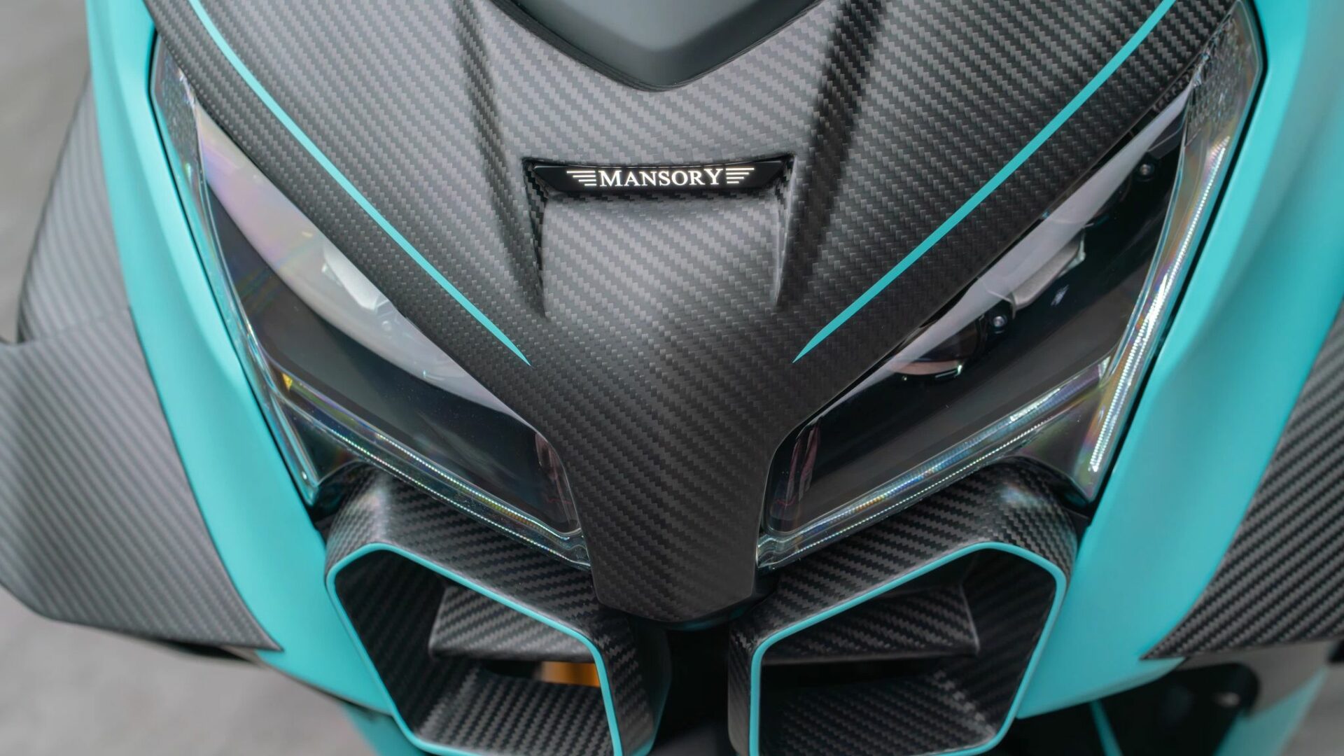 Gros plan sur le masque de phare en carbone avec le logo illuminé Mansory et les prises d'air du Yamaha TMAX 560