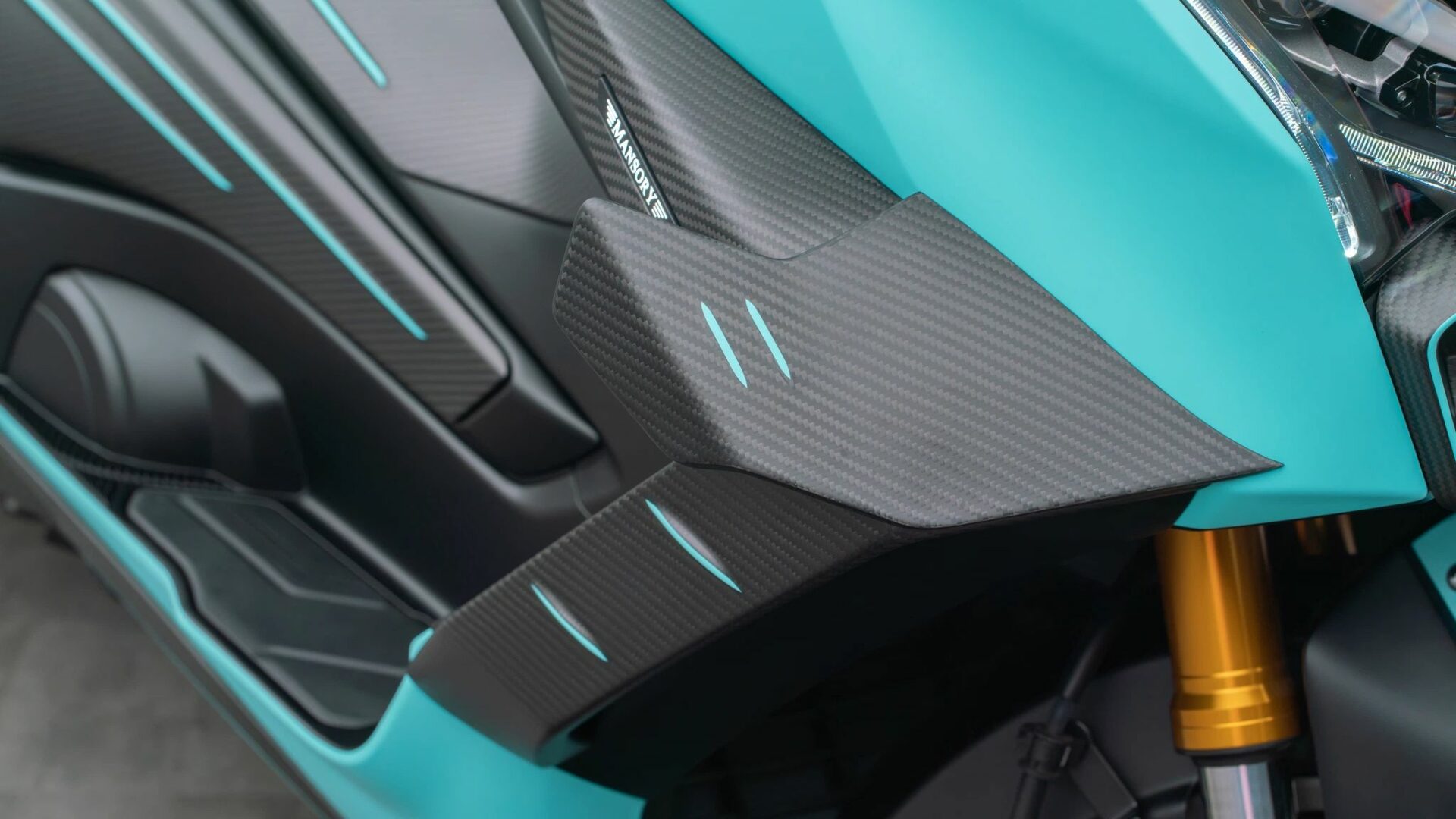 Gros plan sur l'aileron aérodynamique en fibre de carbone et le badge Mansory sur le flanc d'un Yamaha TMAX 560
