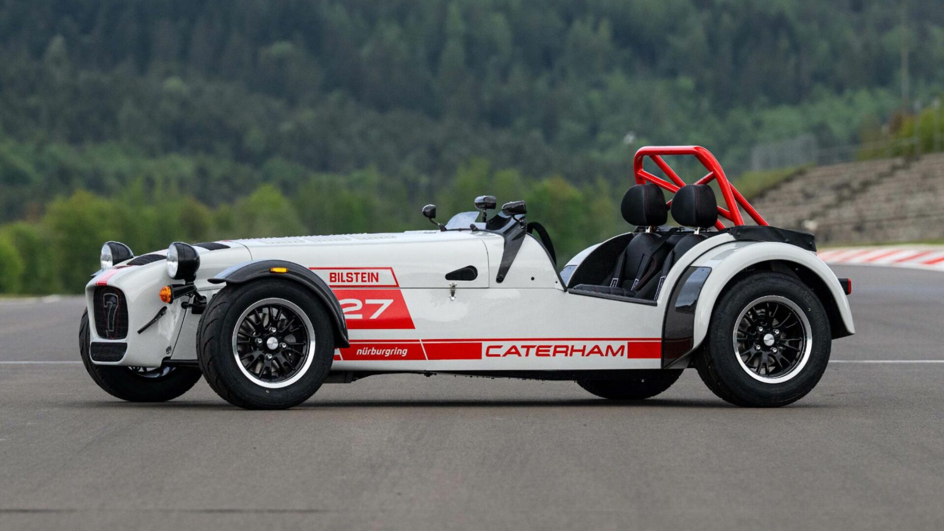 Vue de trois-quarts profil d'une Caterham Seven Nürburgring Edition sur circuit avec livrée blanche et rouge