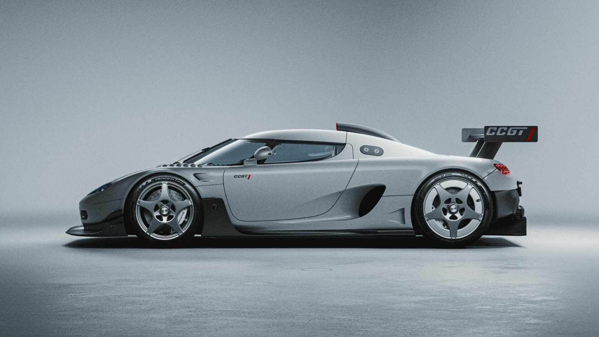Vue de profil de la Koenigsegg CCGT1 argentée montrant sa ligne élancée, sa prise d'air au toit et son imposant aileron arrière GT