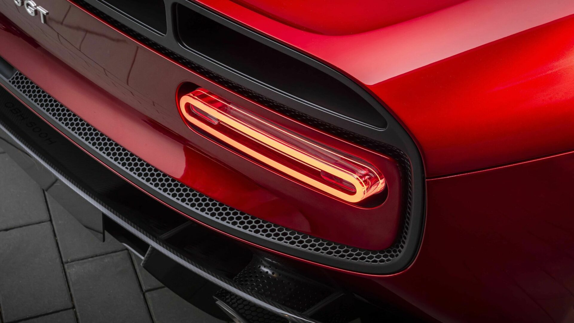 Gros plan sur le feu arrière à LED ovale et lumineux de la McLaren 6GT rouge encastré dans une grille d'aération