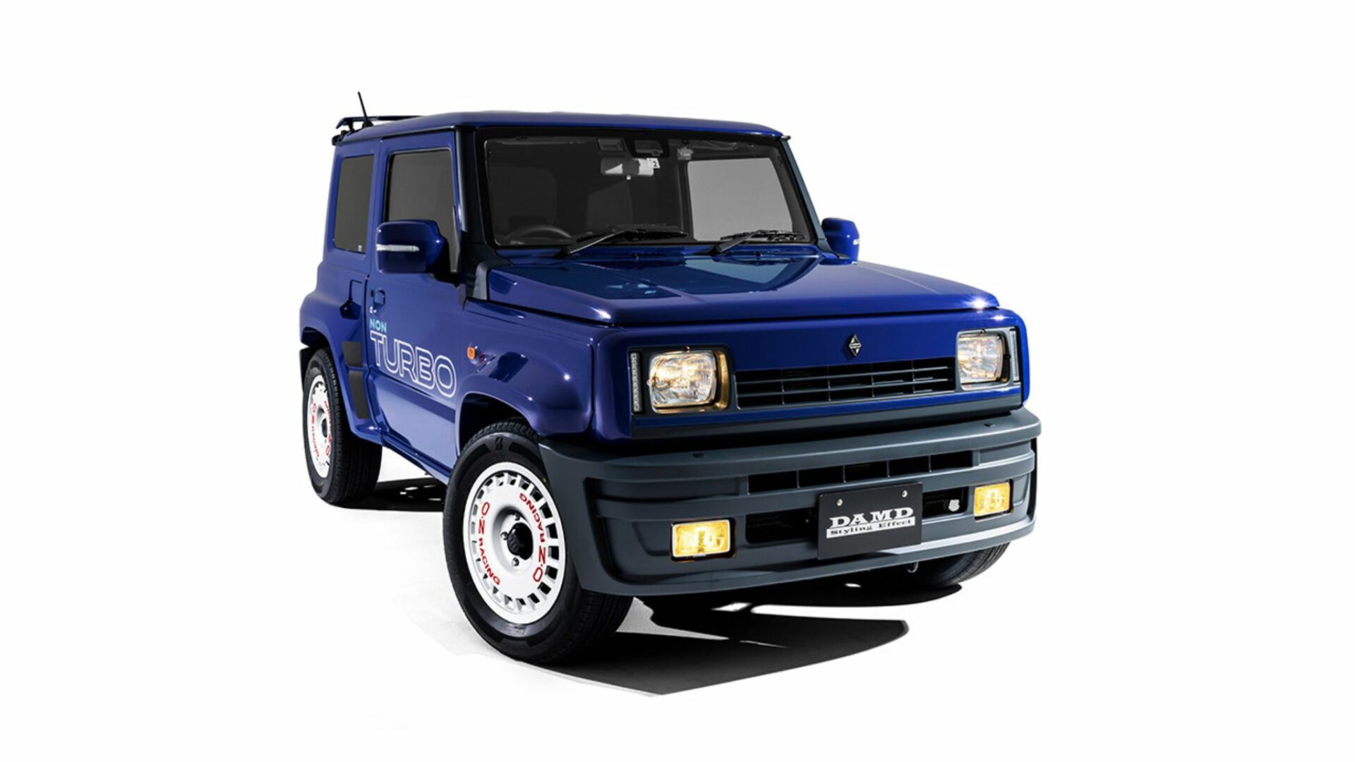Vue trois-quarts avant studio du Suzuki Jimny R5 DAMD bleu avec phares allumés et kit carrosserie R5