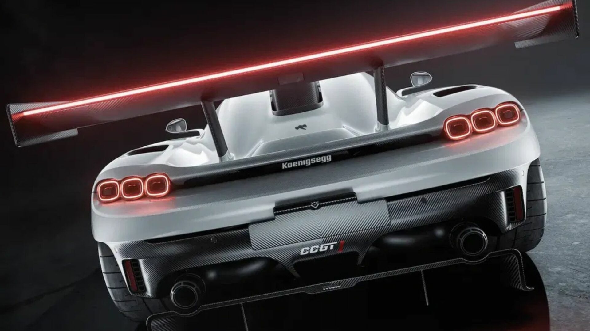 Vue arrière en contre-plongée de la Koenigsegg CCGT1 montrant son imposant aileron en carbone à bandeau LED intégré, ses feux ovales et son diffuseur