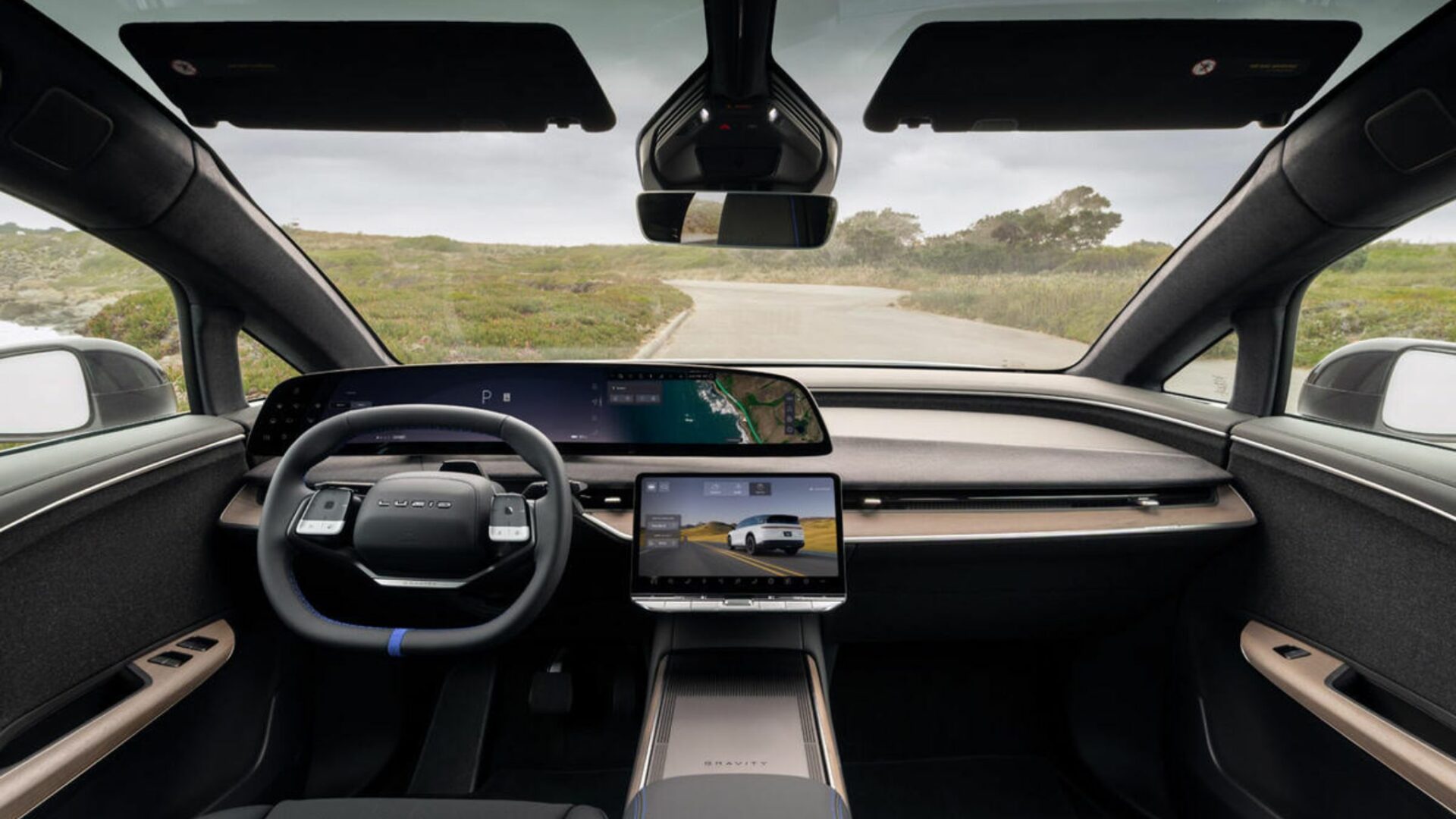 Vue de l'intérieur du Lucid Gravity GT-S montrant le grand écran panoramique incurvé, l'écran central, le volant à méplat avec repère bleu et la planche de bord