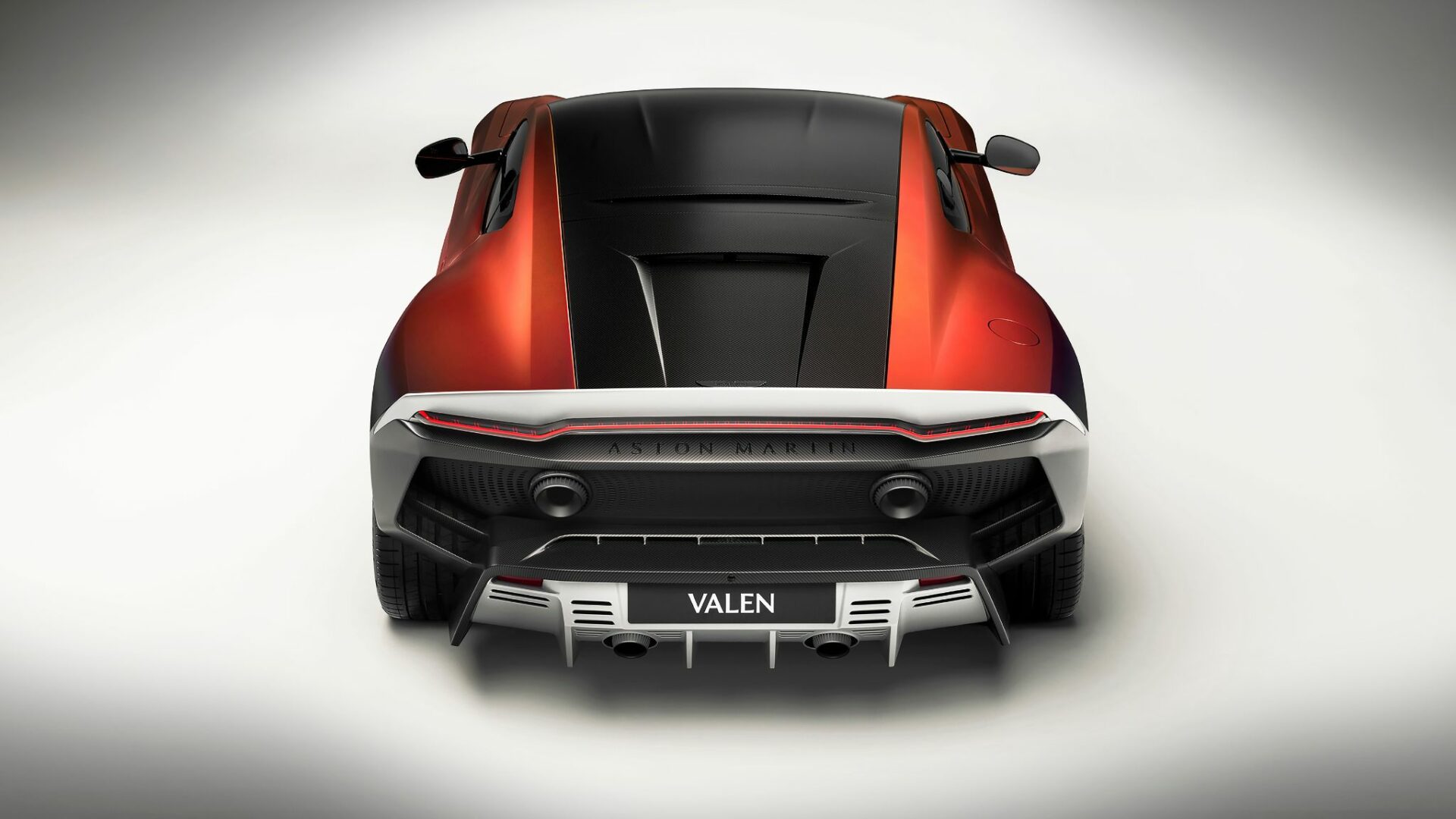 Vue arrière centrée de l'Aston Martin Valen mettant en évidence l'absence de lunette arrière, le bandeau LED traversant et les canules d'échappement