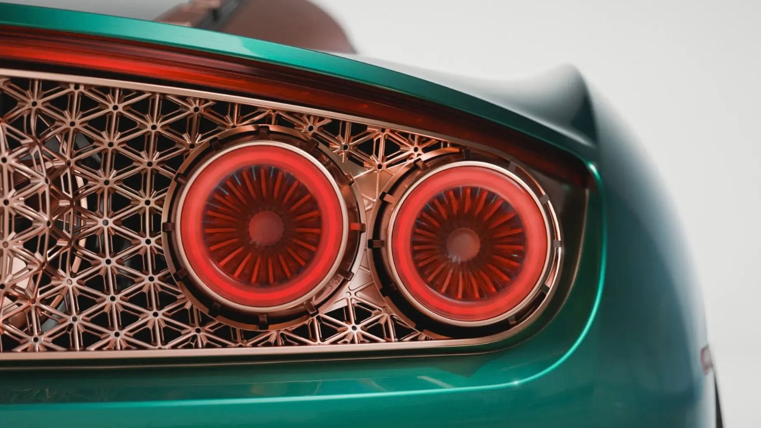 Gros plan sur le feu arrière en forme de tuyère de réacteur de la Spyker C8 Preliator XXV Coupé avec grille en treillis isogrid en or rose et carrosserie Quail Green