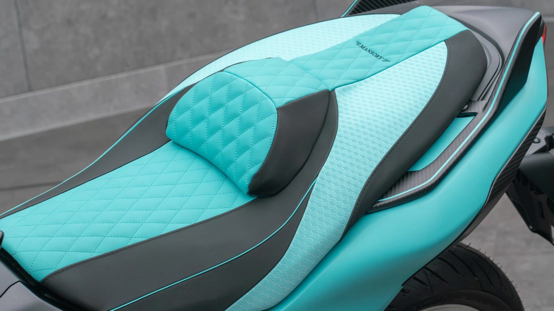 Gros plan sur le travail de sellerie sur-mesure du Mansory T-Max avec cuir matelassé bleu clair, dosseret et logo brodé