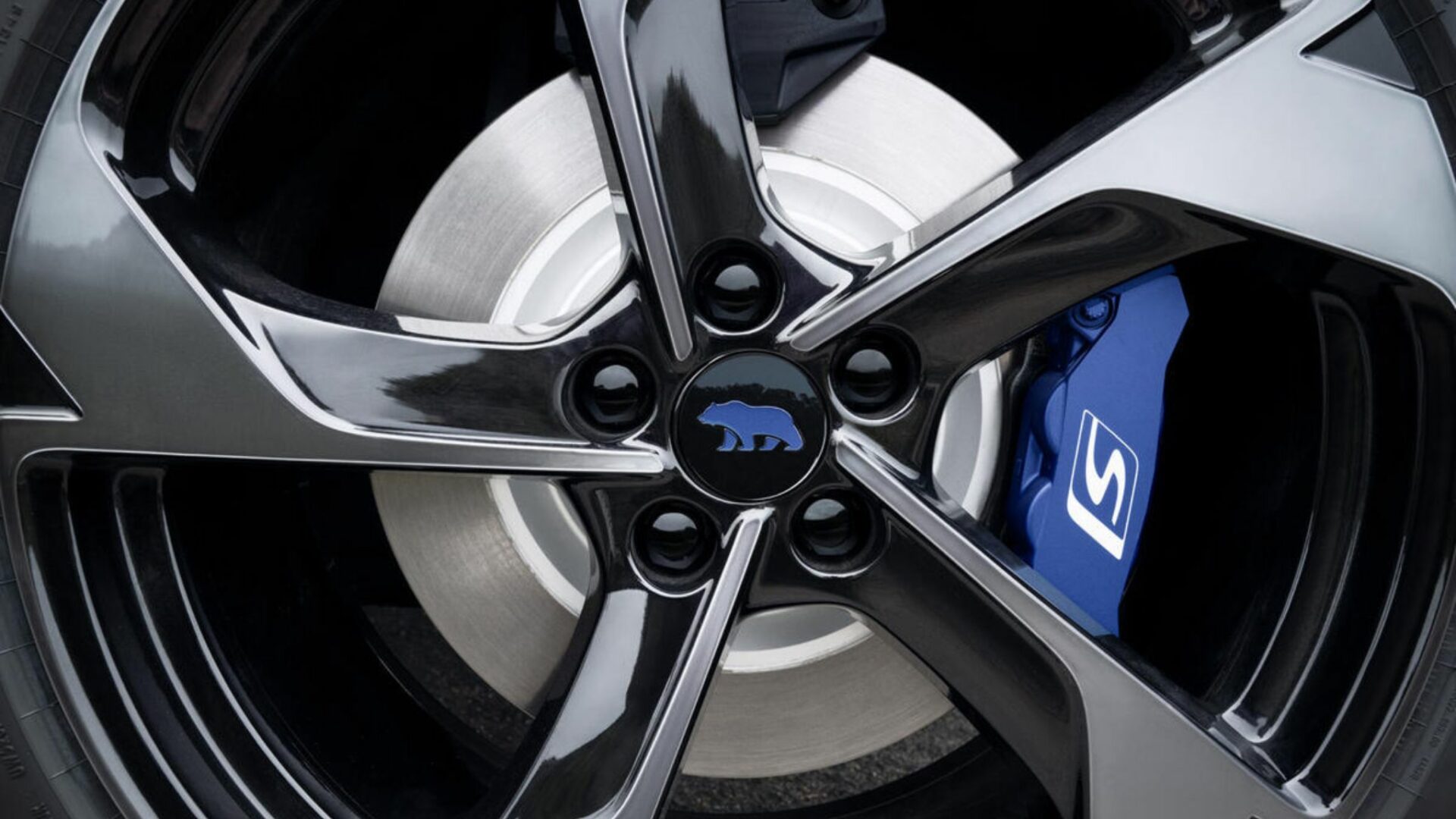 Gros plan sur la jante du Lucid Gravity GT-S avec le centre de roue arborant l'ours bleu Sapphire et l'étrier de frein bleu gravé du logo S
