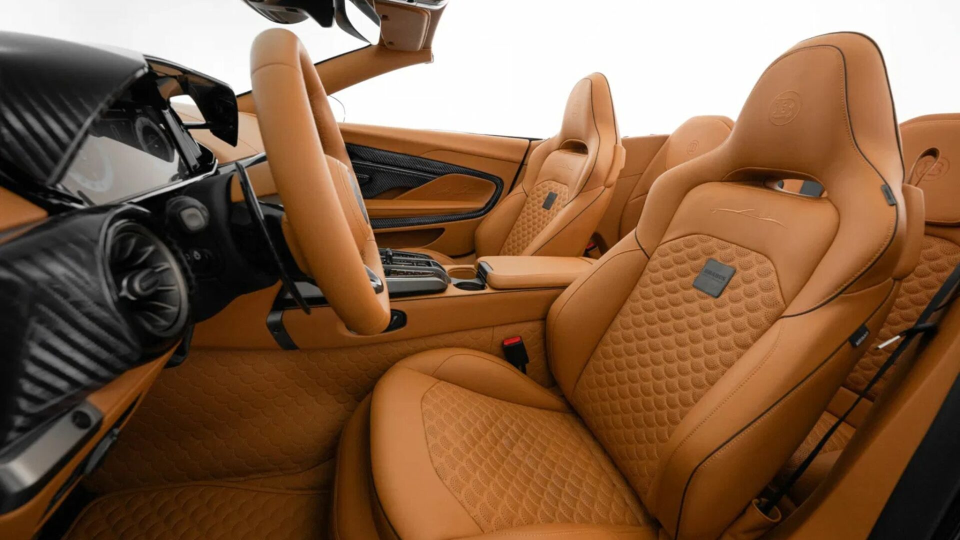 Vue de trois-quarts de l'habitacle de la Brabus Bodo Cabriolet mettant en avant ses sièges baquets en cuir camel matelassé avec badges Brabus et finitions carbone