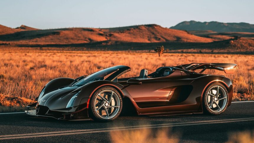 Vue de trois-quarts profil de la Czinger 21C Spyder marron métallique découvrable stationnée sur une route désertique au coucher du soleil