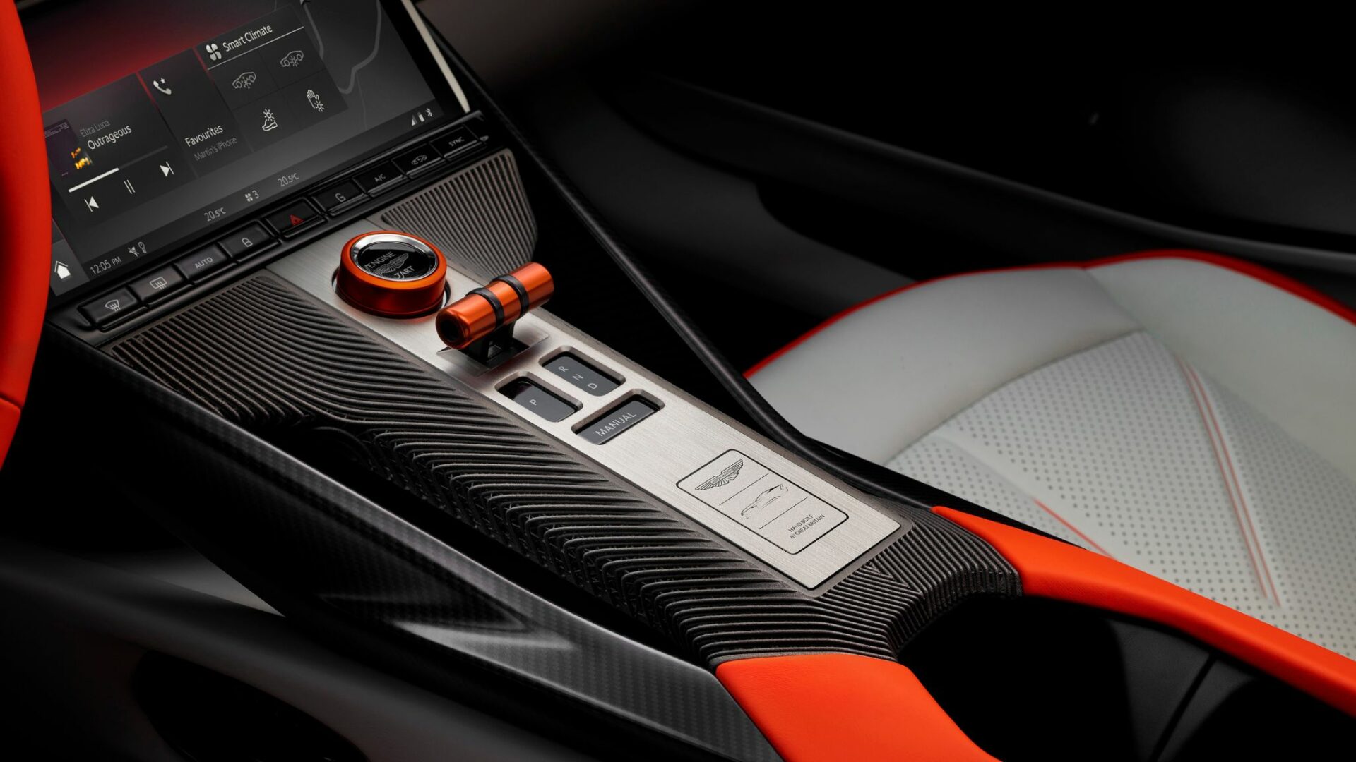 Gros plan sur la console centrale de l'Aston Martin Valen avec le bouton de démarrage orange, le sélecteur de vitesse et la plaque gravée en alu