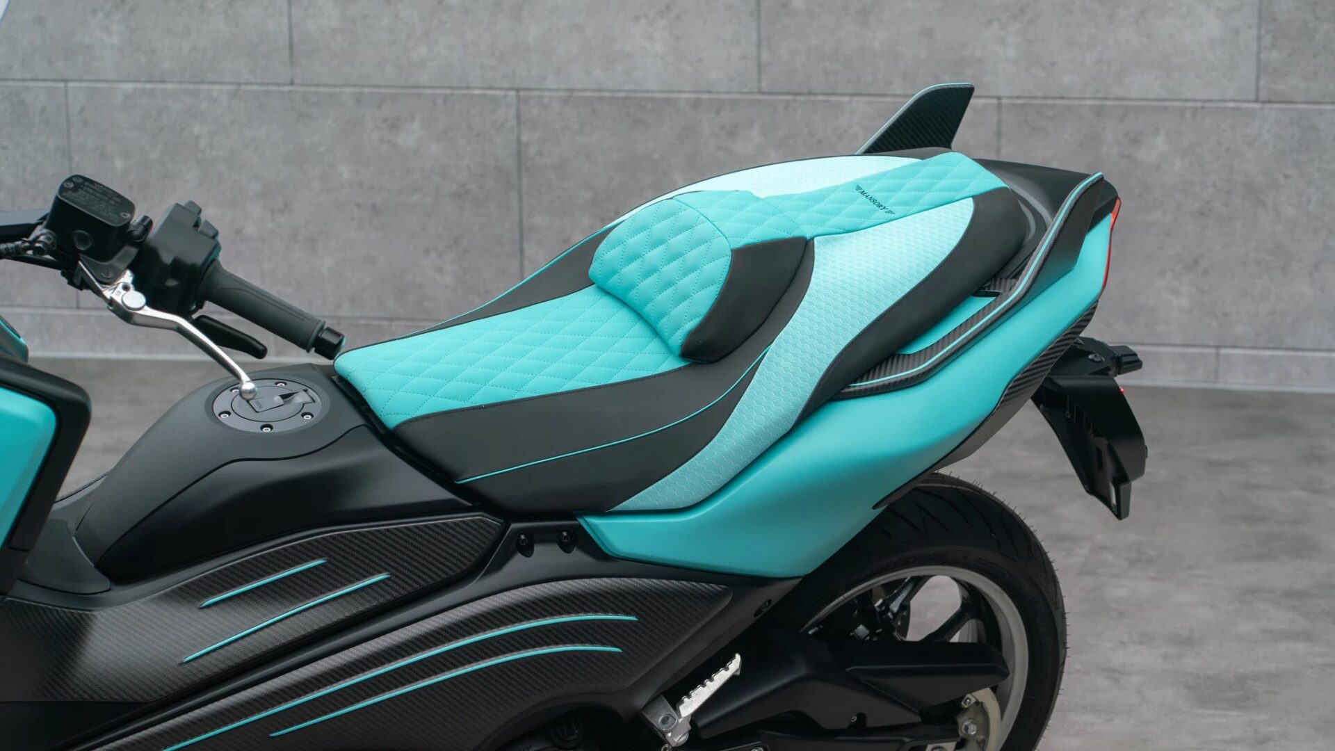 Gros plan sur la selle sur-mesure matelassée bleu et noir et le flanc arrière en carbone du Mansory T-Max
