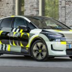 Audi A2 e-tron prototype camouflé stationné de trois-quarts face devant une façade en briques claires