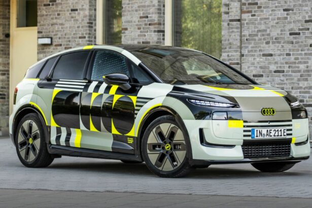 Audi A2 e-tron prototype camouflé stationné de trois-quarts face devant une façade en briques claires