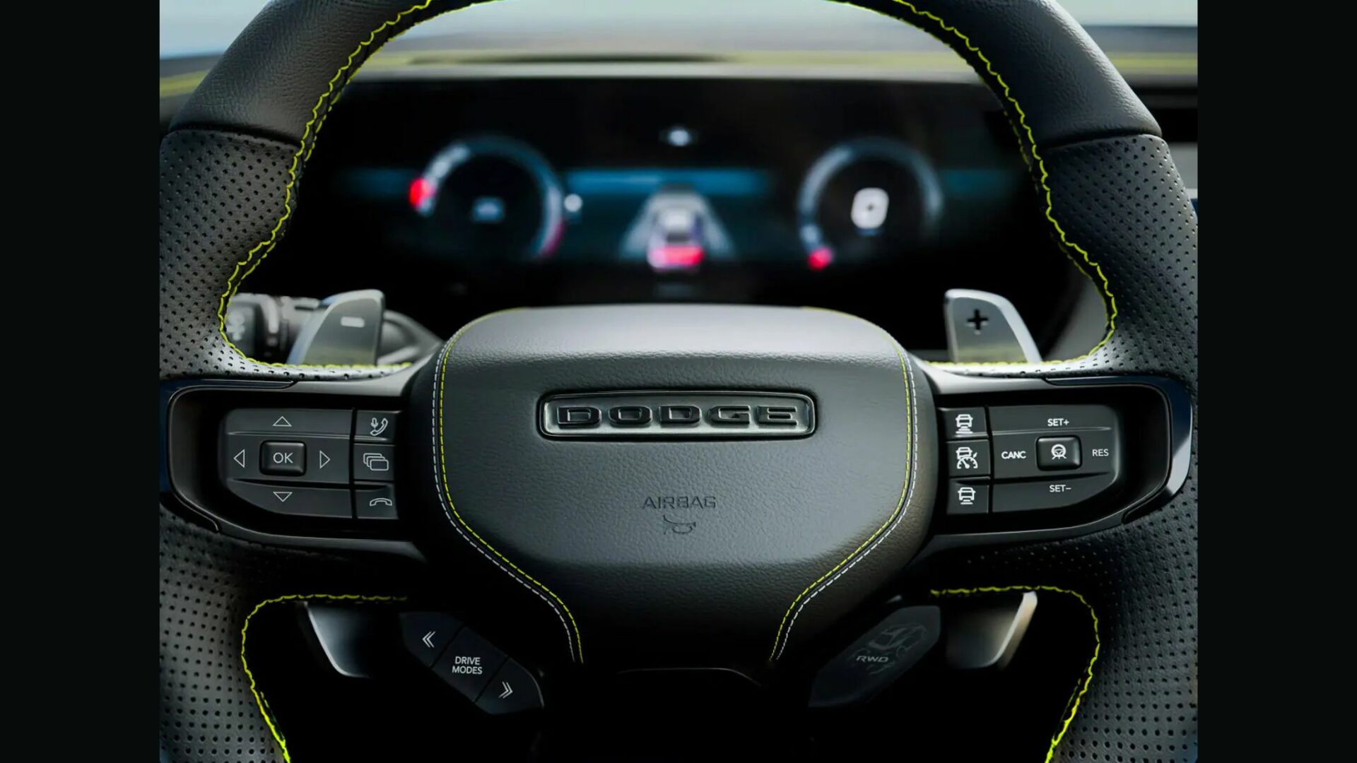Gros plan sur le volant de la Dodge Charger Super Bee 2027 montrant les surpiqûres jaunes, les palettes et le bouton RWD