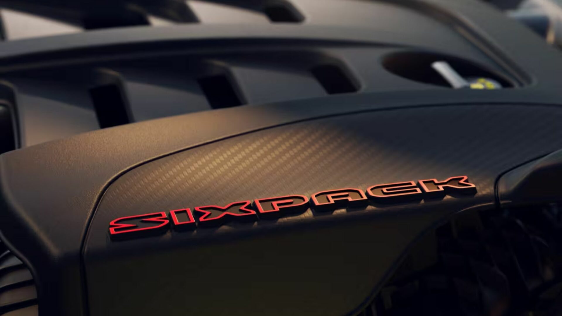Gros plan sur l'inscription SIXPACK en lettres rouges sur le cache-moteur en fibre de carbone de la Dodge Charger Super Bee 2027