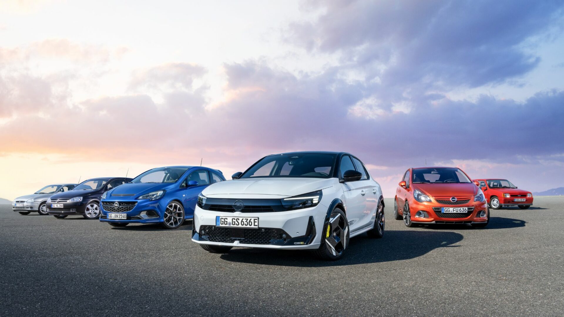 La nouvelle Opel Corsa GSE blanche entourée des anciennes générations Corsa GSi et Corsa OPC au coucher du soleil