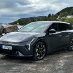 Vue de trois quarts avant de la nouvelle Kia EV4 GT grise garée sur un site côtier rocailleux face à un fjord et des montagnes en Norvège.