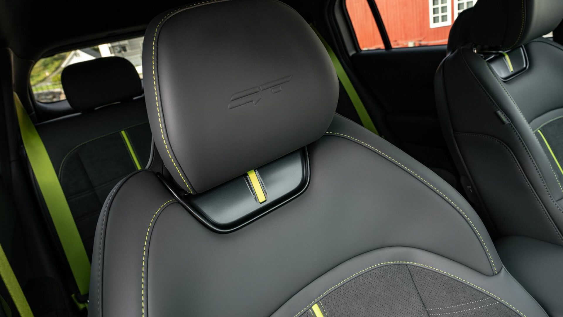 Gros plan sur l'appui-tête et le haut d'un siège sport semi-baquet en suédine de la Kia EV3 GT, arborant le logo GT embossé et des touches de couleur Vert Néon.