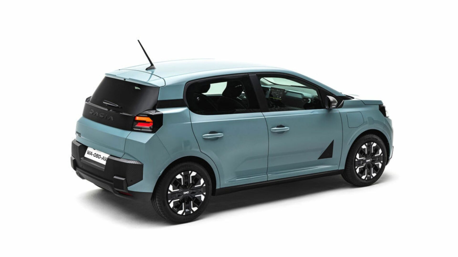 Vue aérienne de trois quarts arrière de la Nouvelle Dacia Spring dans sa livrée Agave, dévoilant son optique arrière et son hayon.