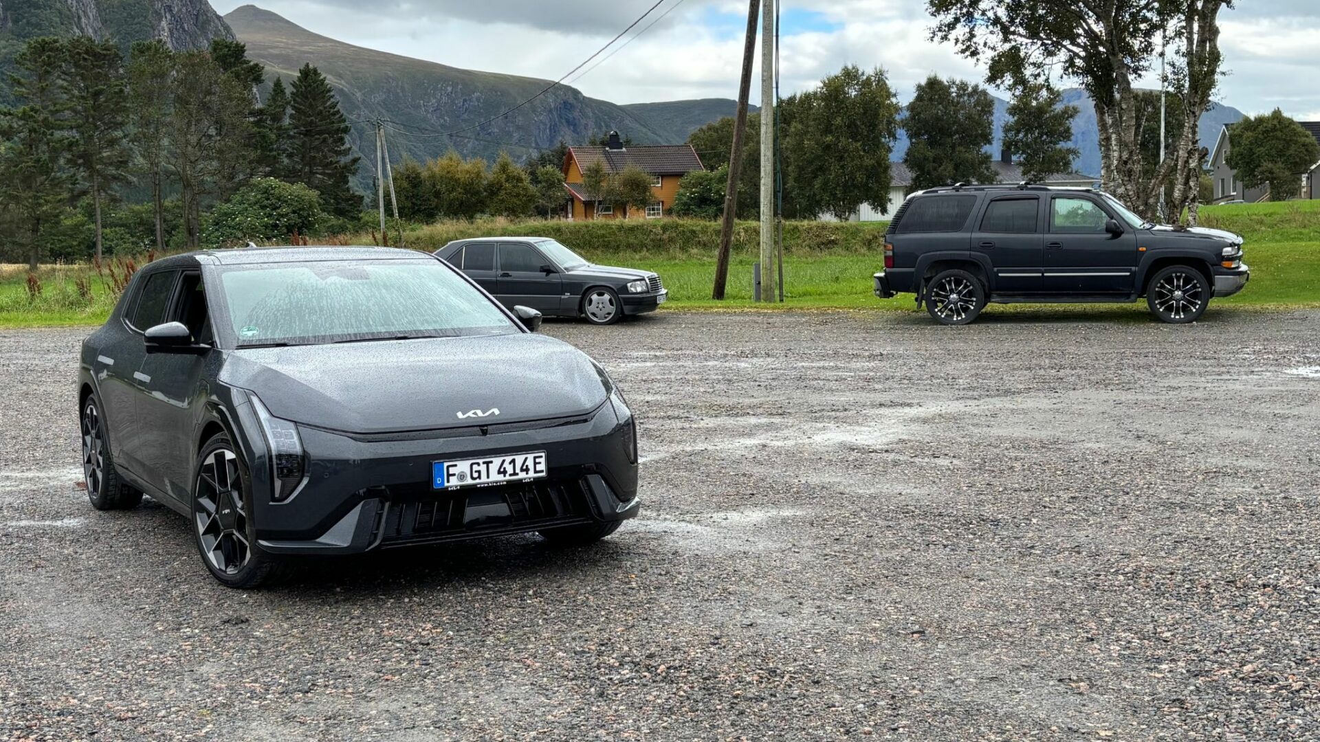 Vue de trois quarts avant de la nouvelle Kia EV4 GT grise stationnée sur un grand parking gravillonné en Norvège, aux côtés d'autres véhicules.