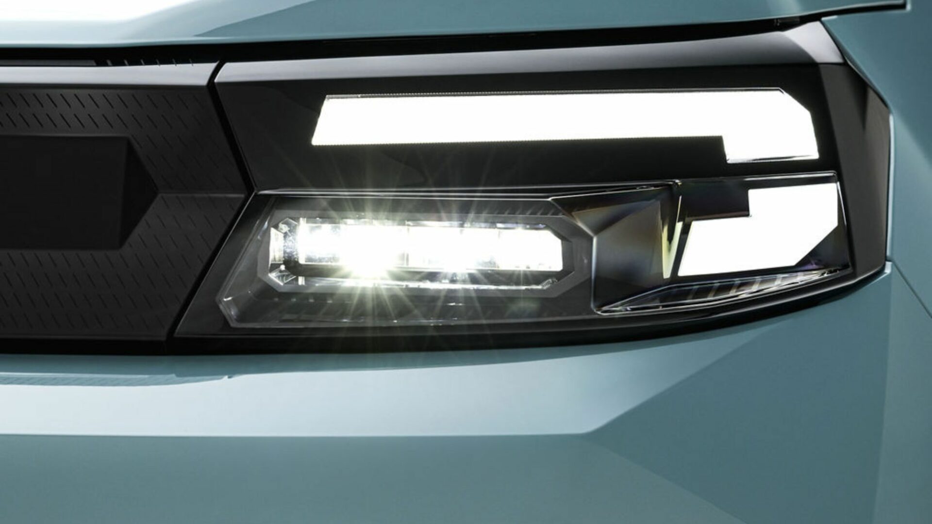 Gros plan sur le projecteur avant et la signature lumineuse LED en forme de Y de la Nouvelle Dacia Spring.