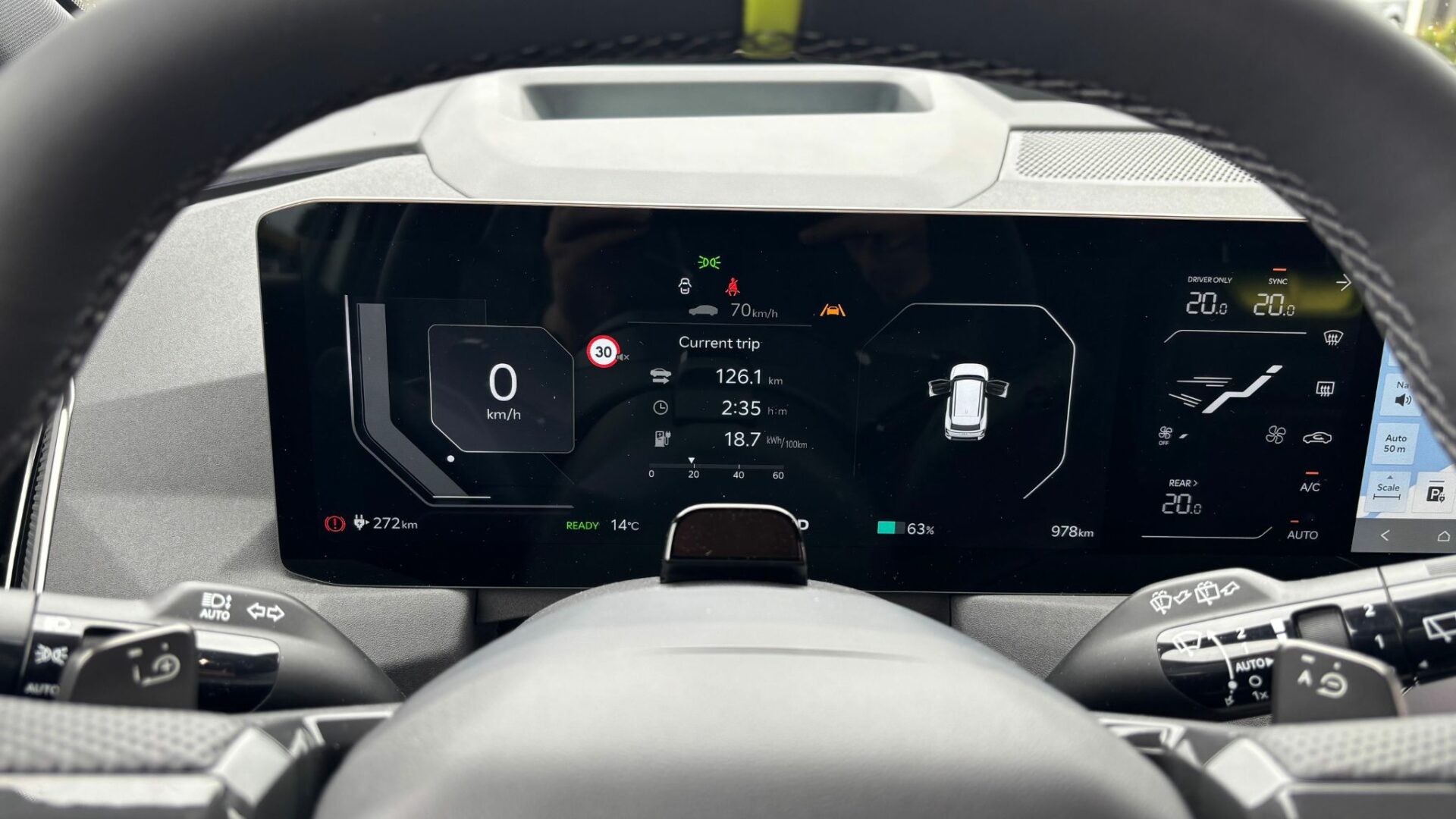 Vue de l'instrumentation numérique derrière le volant de la Kia EV5 GT, affichant les informations du trajet en cours, notamment une consommation moyenne de 18,7 kWh / 100 km.