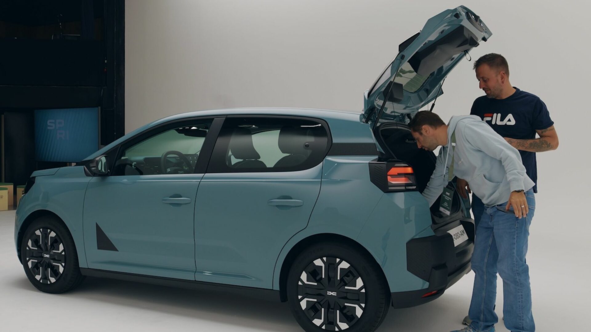 Le célèbre youtubeur automobile Victor Diakov observe un autre journaliste tester le coffre de 337 litres de la Nouvelle Dacia Spring.