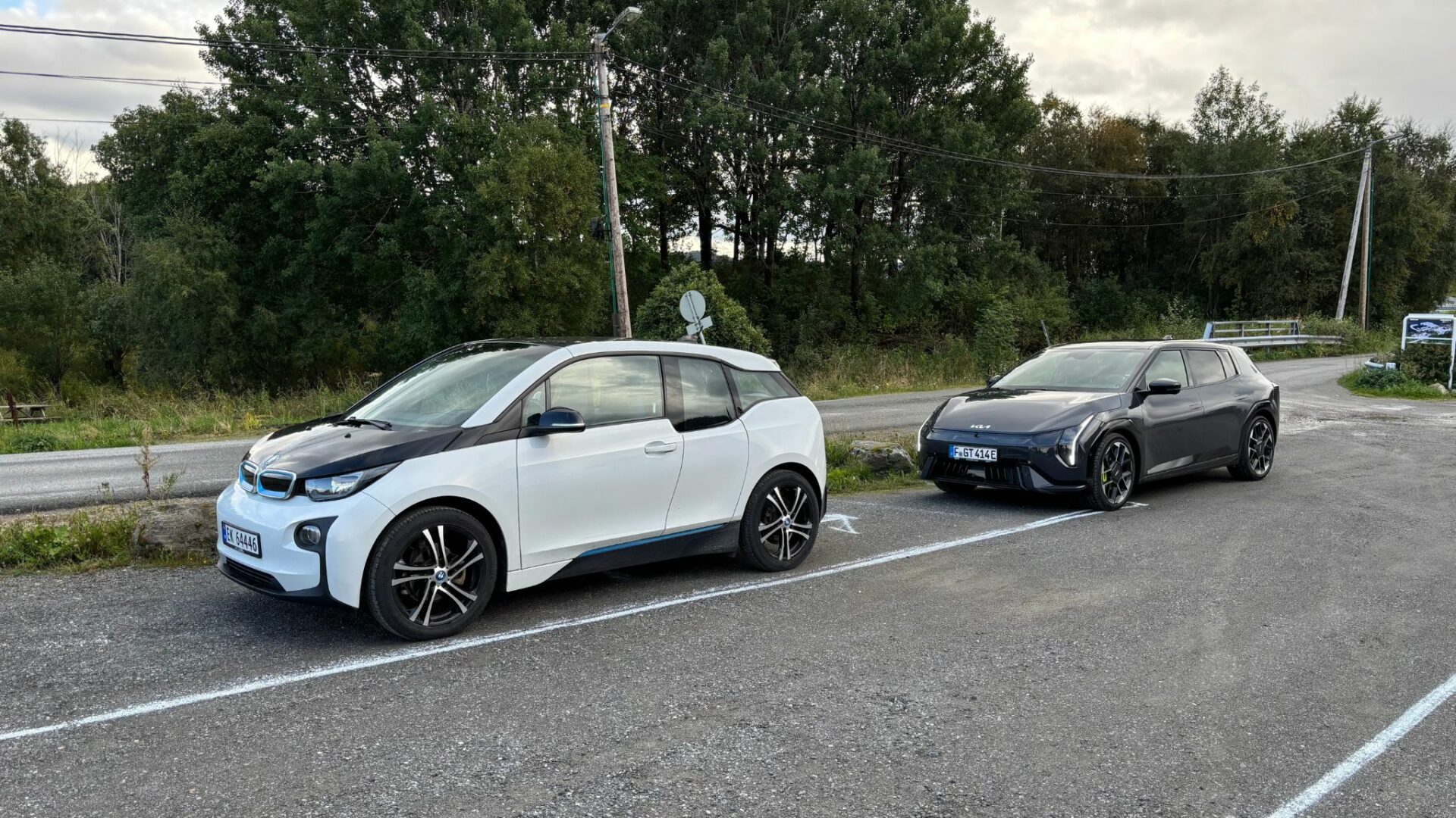 La nouvelle Kia EV4 GT grise garée sur un parking aux côtés d'une BMW i3 blanche lors des essais sur route en Norvège.